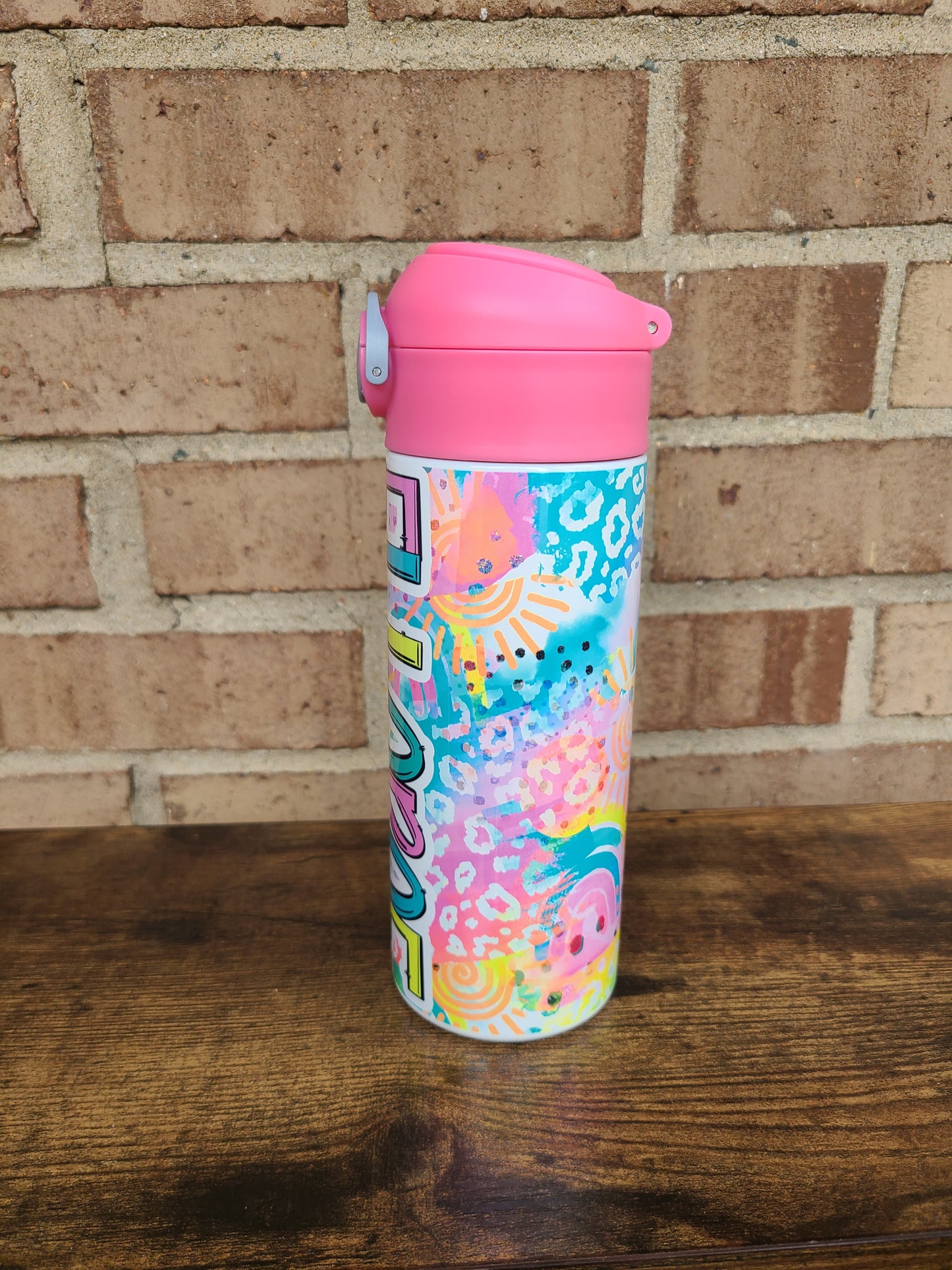 12oz water bottle with pink lid that has a built in straw, locking push button and handle. This design features bright colored animal print with sunshine and rainbows. Personalized in coordinating bright colors with a pink lid. Back to school.