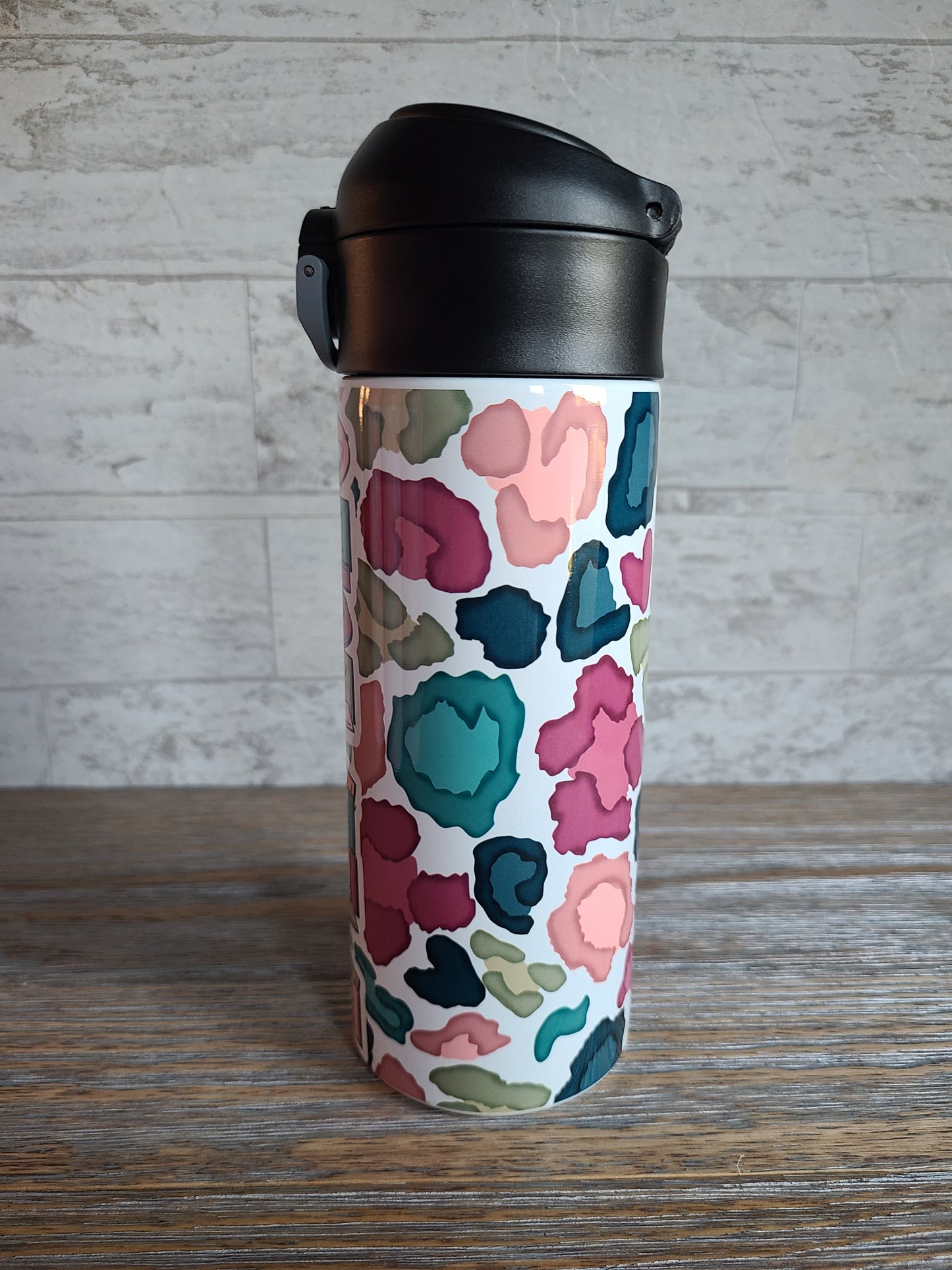 12 oz water bottle with a black lid that has a built-in straw, locking push button and handle. This design features a white background multi-colored leopard print. Personalized in coordinating colors.
