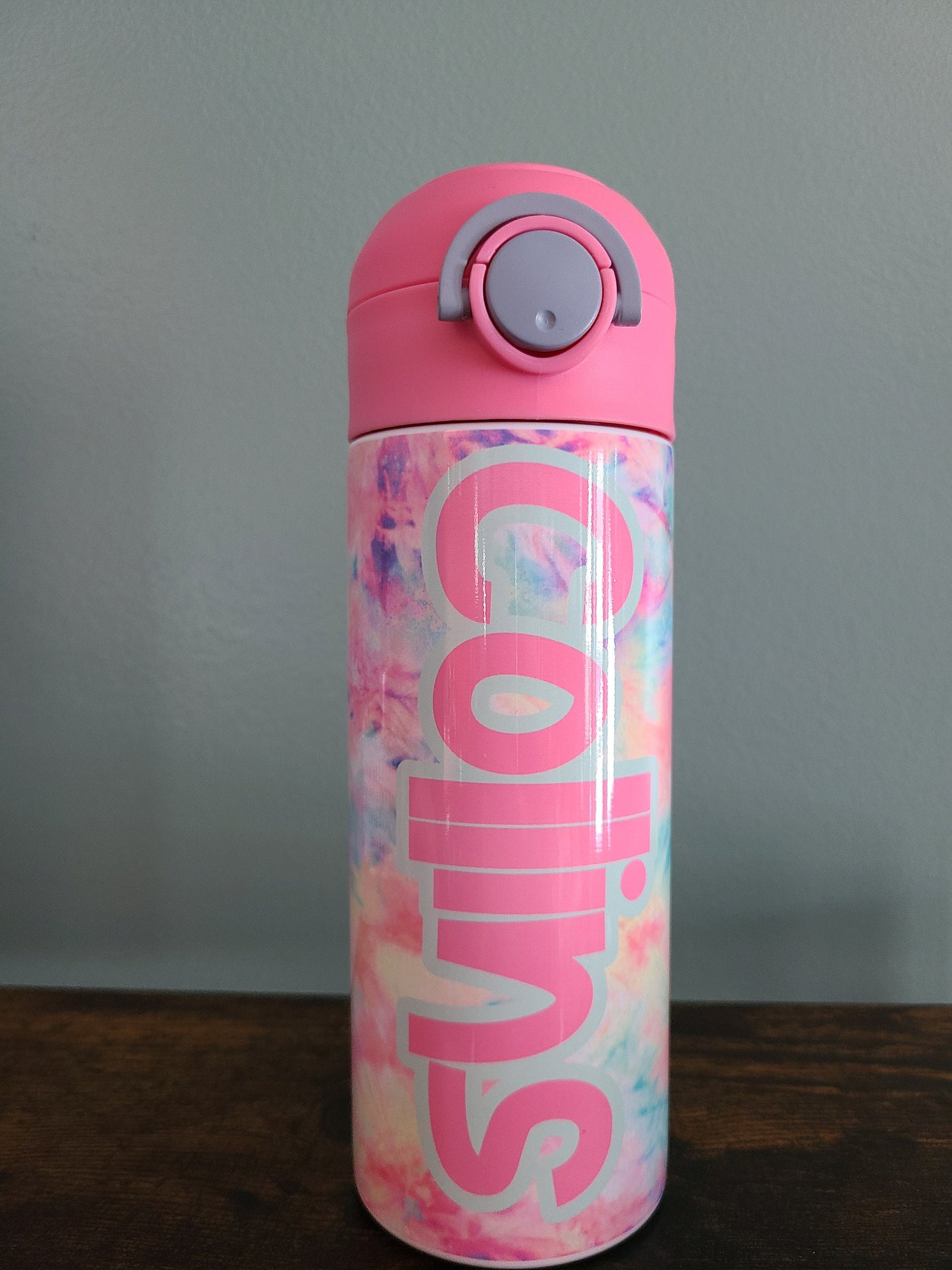 12 oz water bottle with flip top and built in straw. Pink tie dye themed water bottle for kids. Back to school water bottle for kids. Tie dye in pastel colors with a name in pink and pink lid.