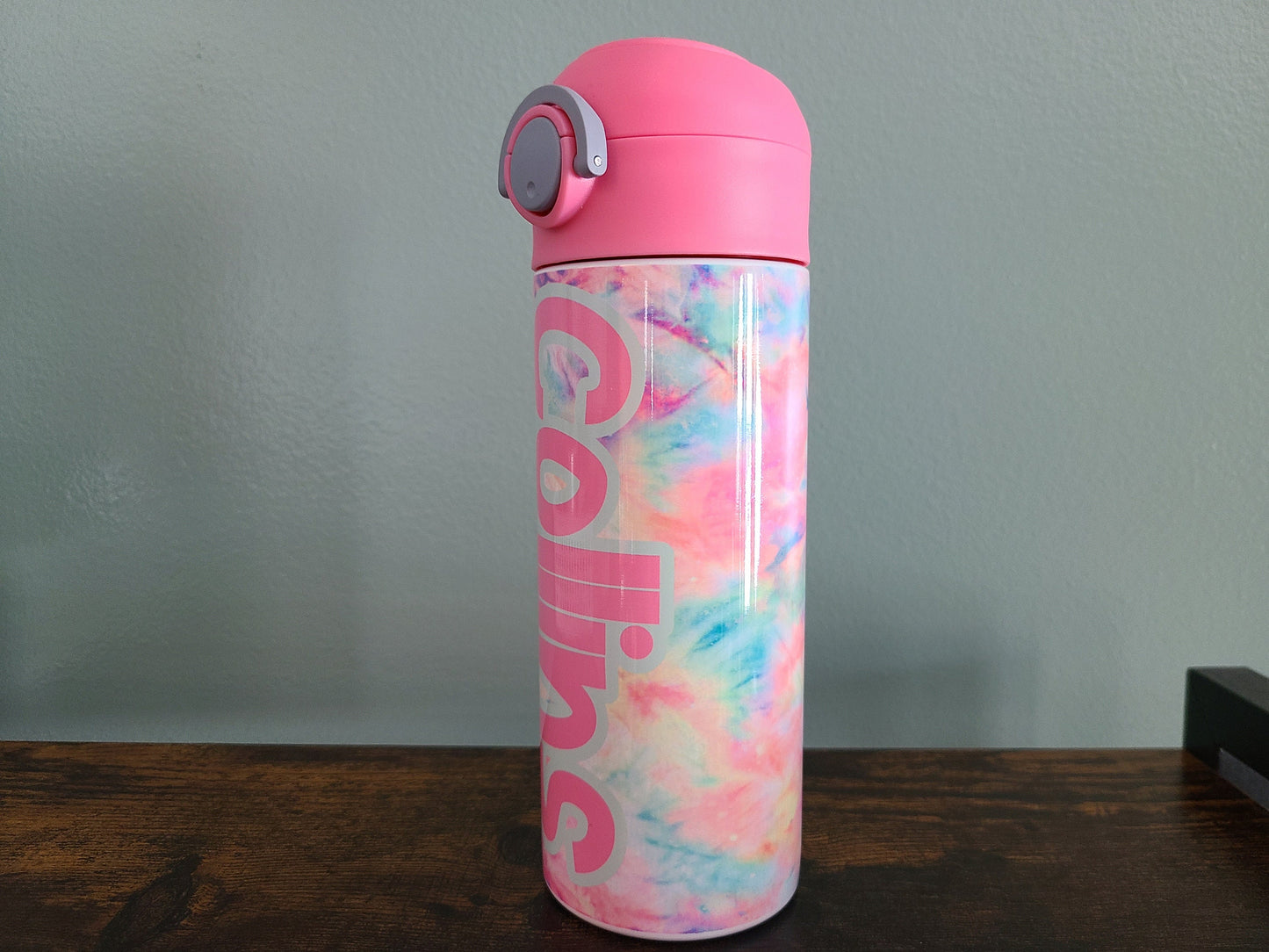 12 oz water bottle with flip top and built in straw. Pink tie dye themed water bottle for kids. Back to school water bottle for kids. Tie dye in pastel colors with a name in pink and pink lid.