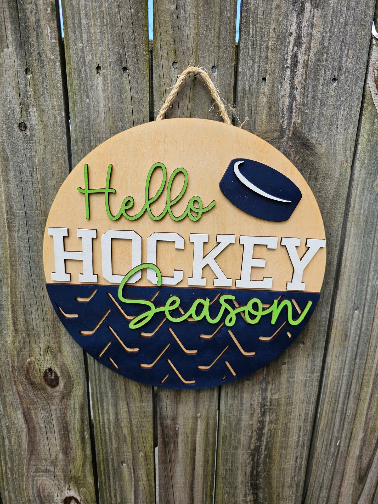 Round wooden sign with 'Hello Hockey Season' text and hockey puck design on a wooden background