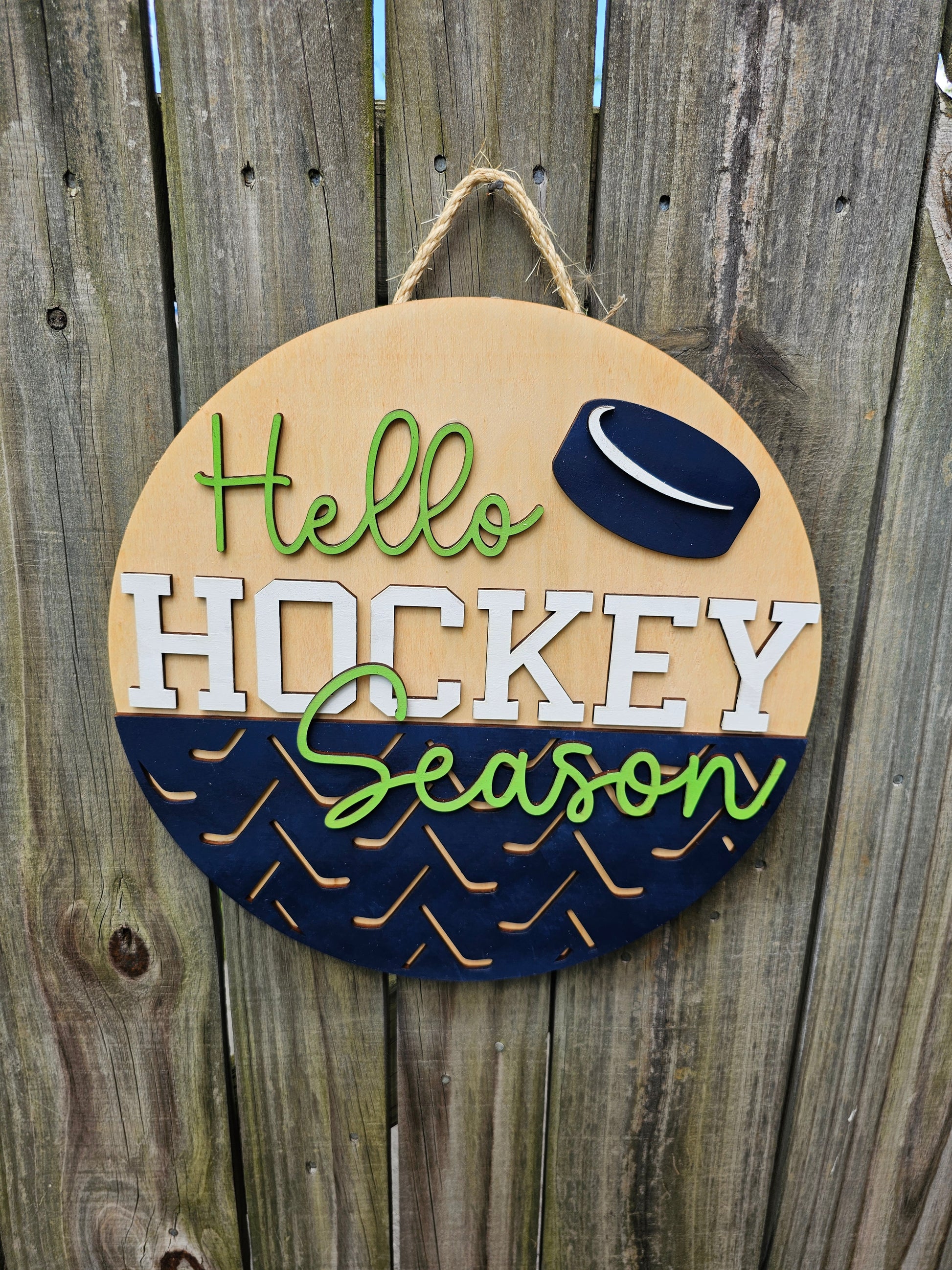 Round wooden sign with 'Hello Hockey Season' text and hockey puck design on a wooden background