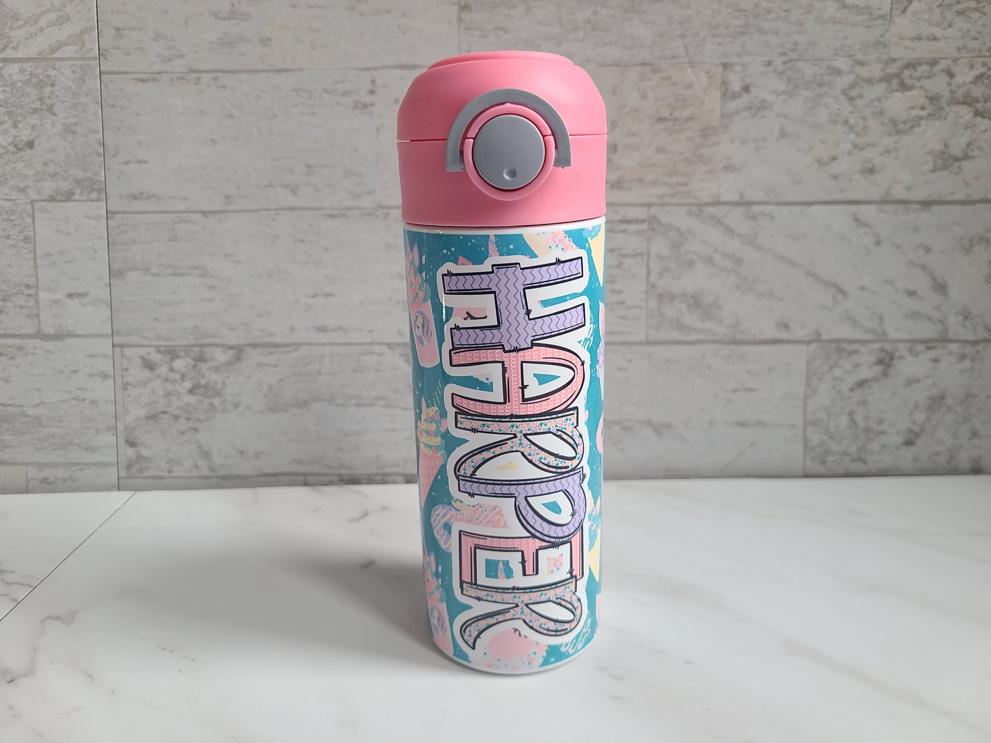 12 oz water bottle with pink lid that has a built-in straw, locking push button and handle. This design features pastel unicorn cupcakes and ice cream cones. Personalized in coordinating colors. Back to School.