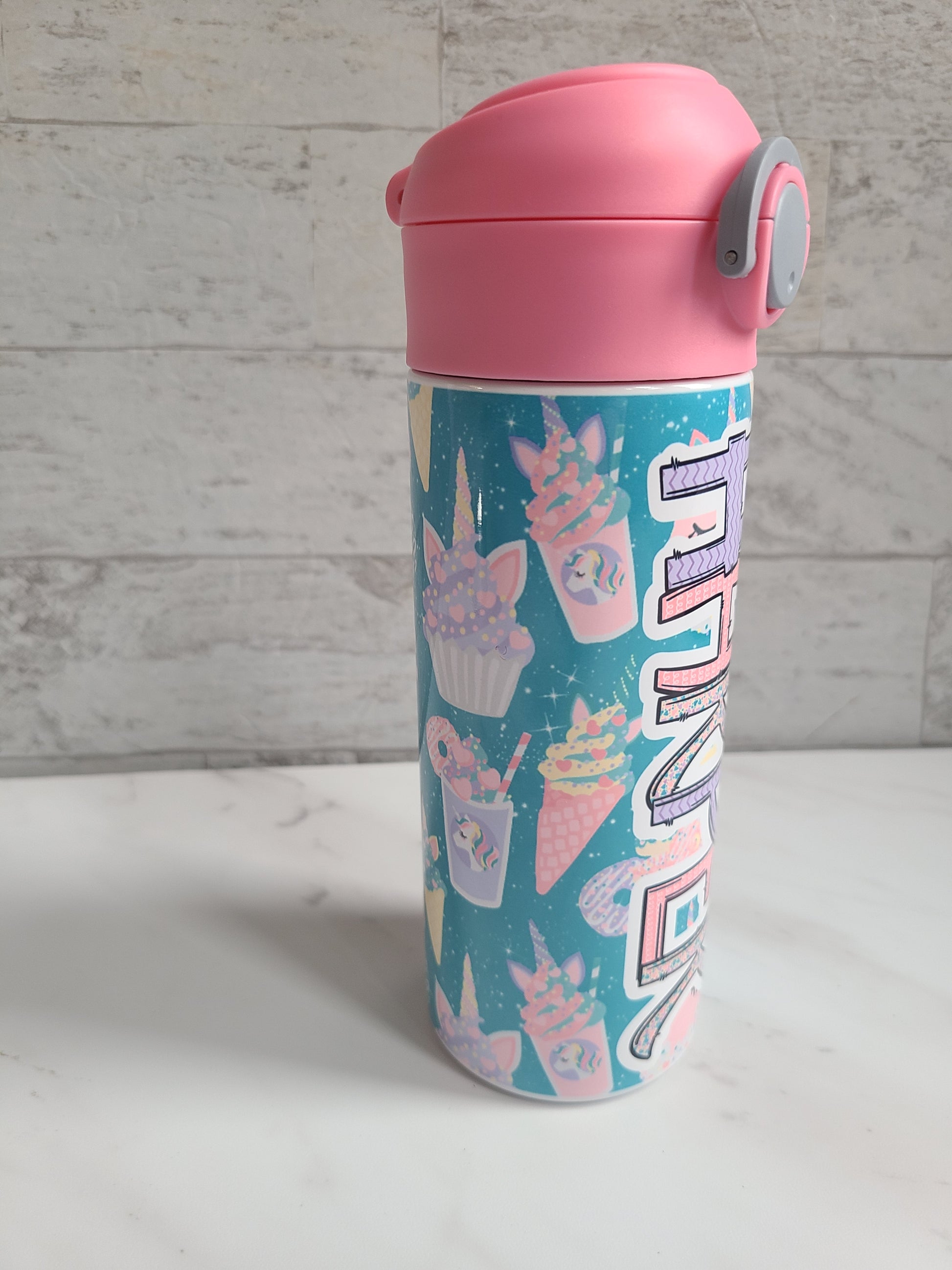 12 oz water bottle with pink lid that has a built-in straw, locking push button and handle. This design features pastel unicorn cupcakes and ice cream cones. Personalized in coordinating colors. Back to School.