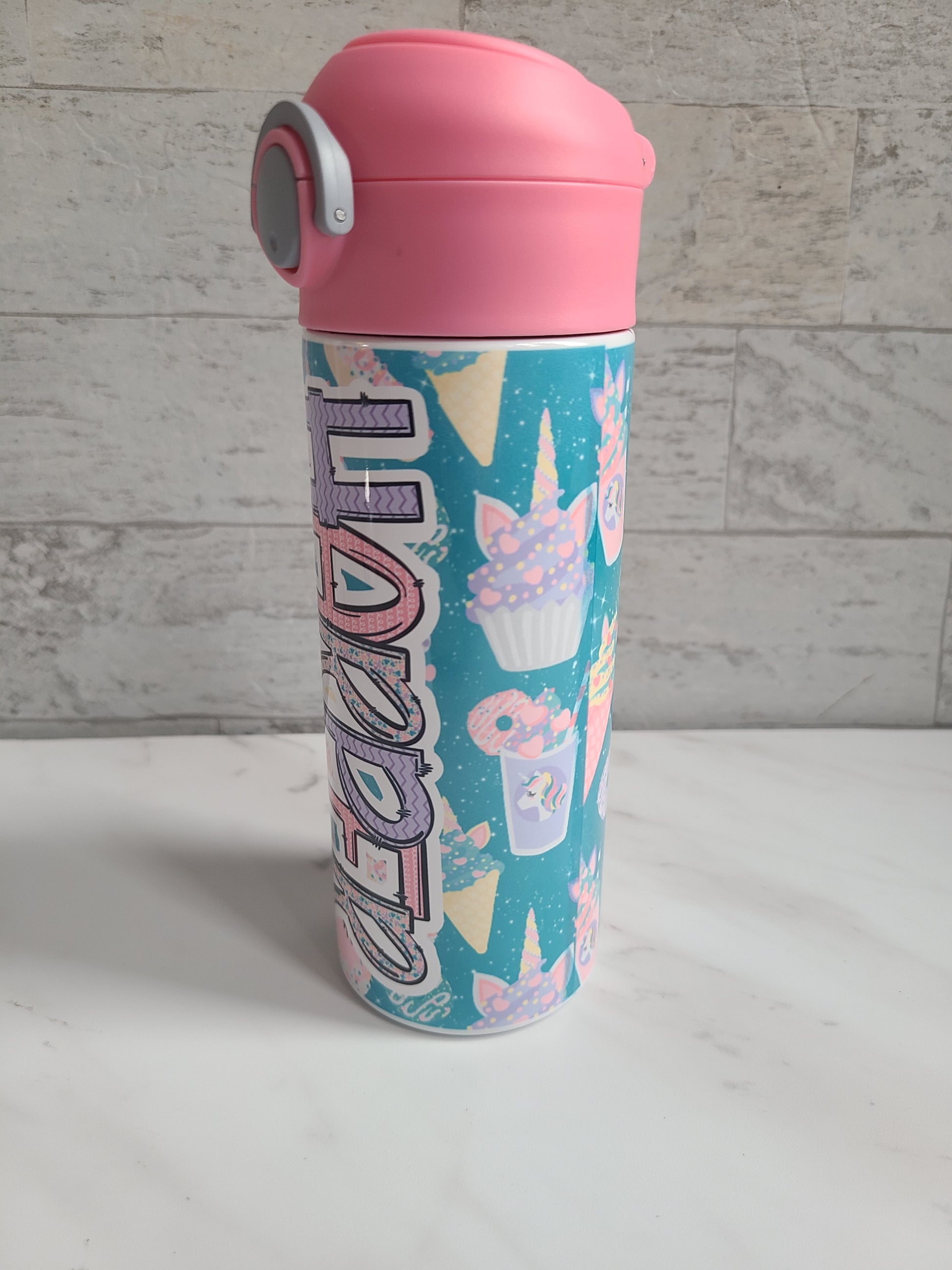 12 oz water bottle with pink lid that has a built-in straw, locking push button and handle. This design features pastel unicorn cupcakes and ice cream cones. Personalized in coordinating colors. Back to School.