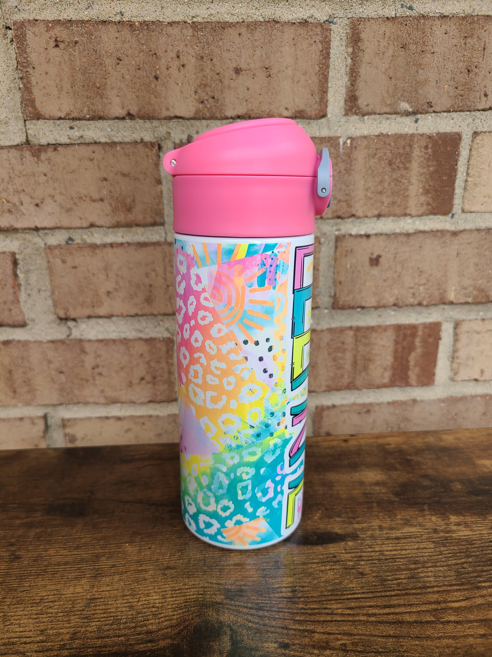 12oz water bottle with pink lid that has a built in straw, locking push button and handle. This design features bright colored animal print with sunshine and rainbows. Personalized in coordinating bright colors with a pink lid. Back to school.