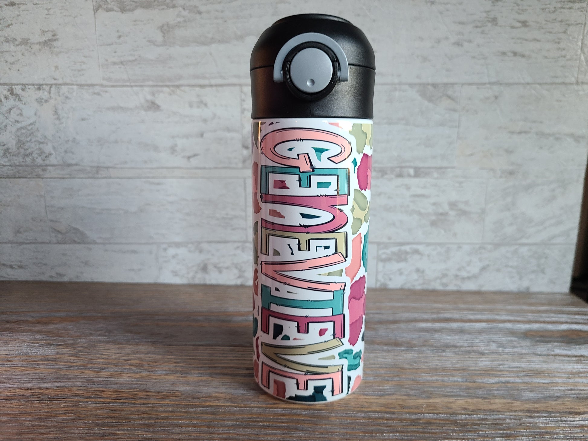  12 oz water bottle with a black lid that has a built-in straw, locking push button and handle. This design features a white background multi-colored leopard print. Personalized in coordinating colors. Back to School.