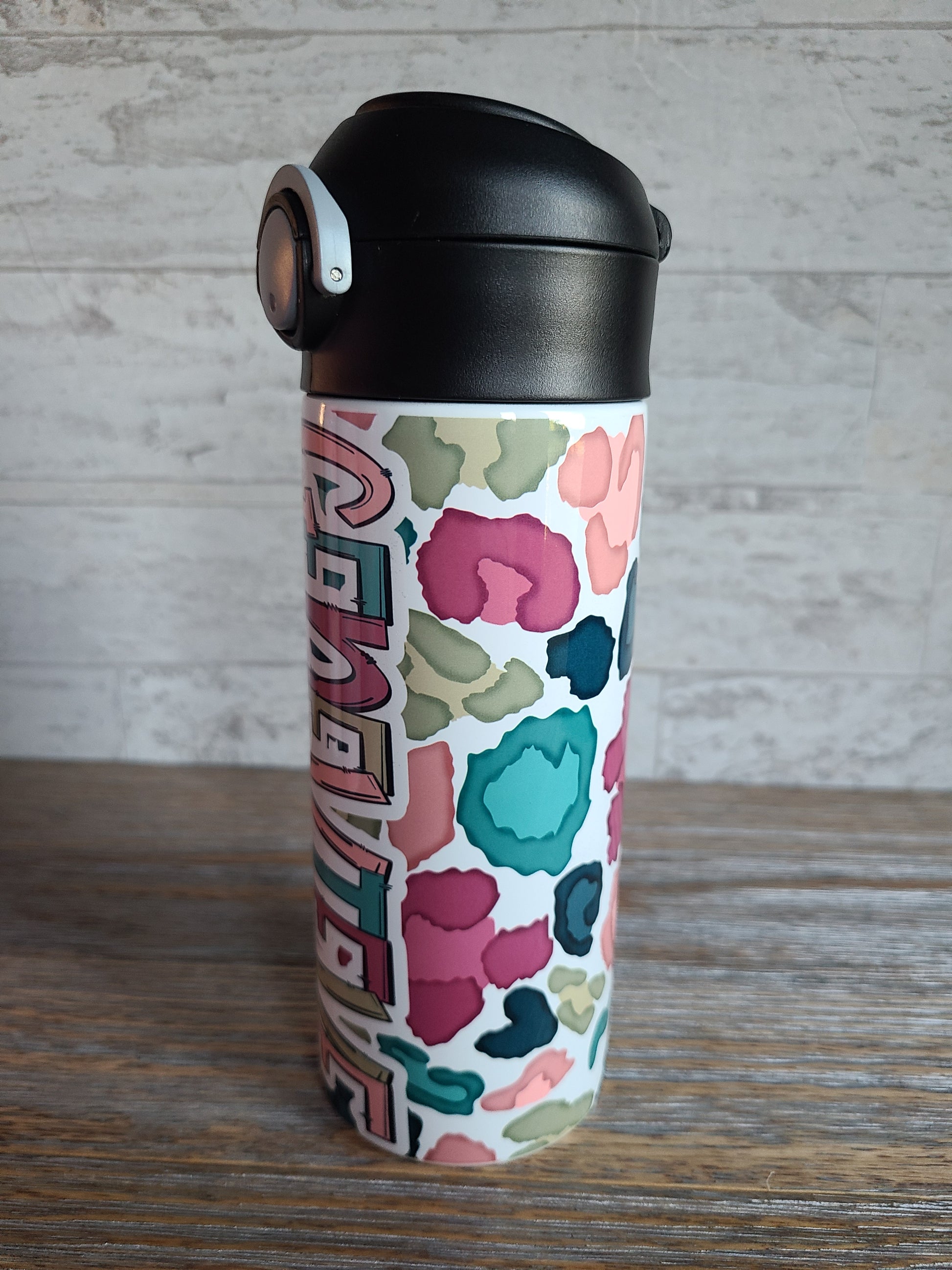 12 oz water bottle with a black lid that has a built-in straw, locking push button and handle. This design features a white background multi-colored leopard print. Personalized in coordinating colors. Back to School.