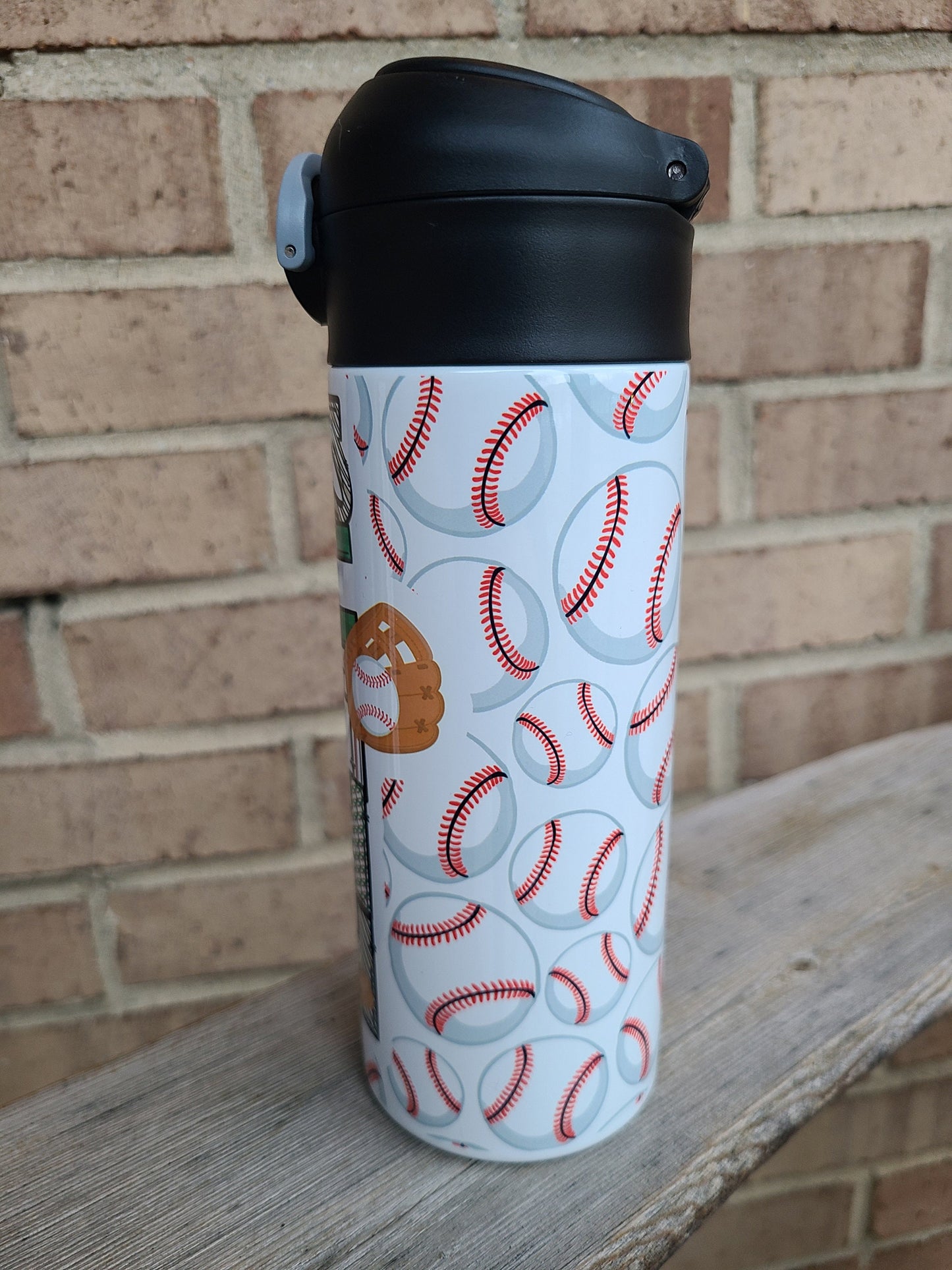12 oz water bottle with a black lid that has a built-in straw, locking push button and handle. This design features multiple baseballs with a glove and bat print. Personalized in coordinating colors. Back to School.