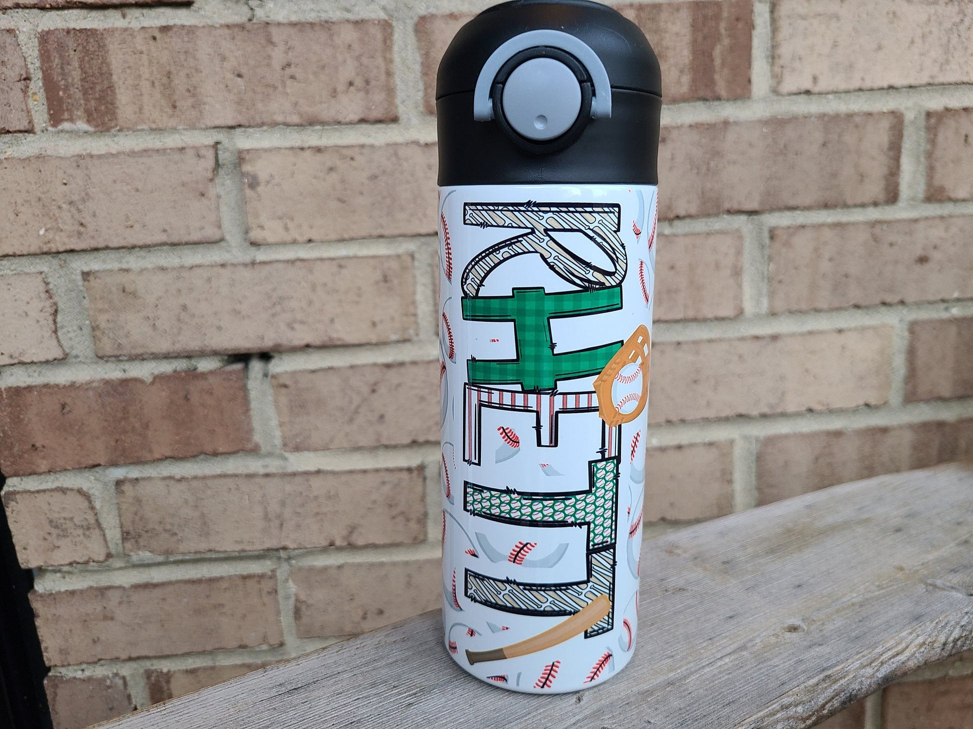 12 oz water bottle with a black lid that has a built-in straw, locking push button and handle. This design features multiple baseballs with a glove and bat print. Personalized in coordinating colors. Back to School.
