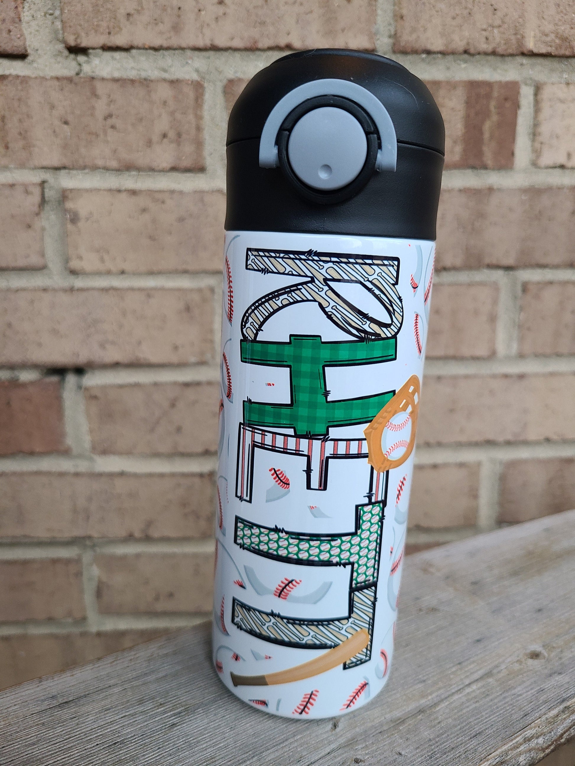 12 oz water bottle with a black lid that has a built-in straw, locking push button and handle. This design features multiple baseballs with a glove and bat print. Personalized in coordinating colors. Back to School.