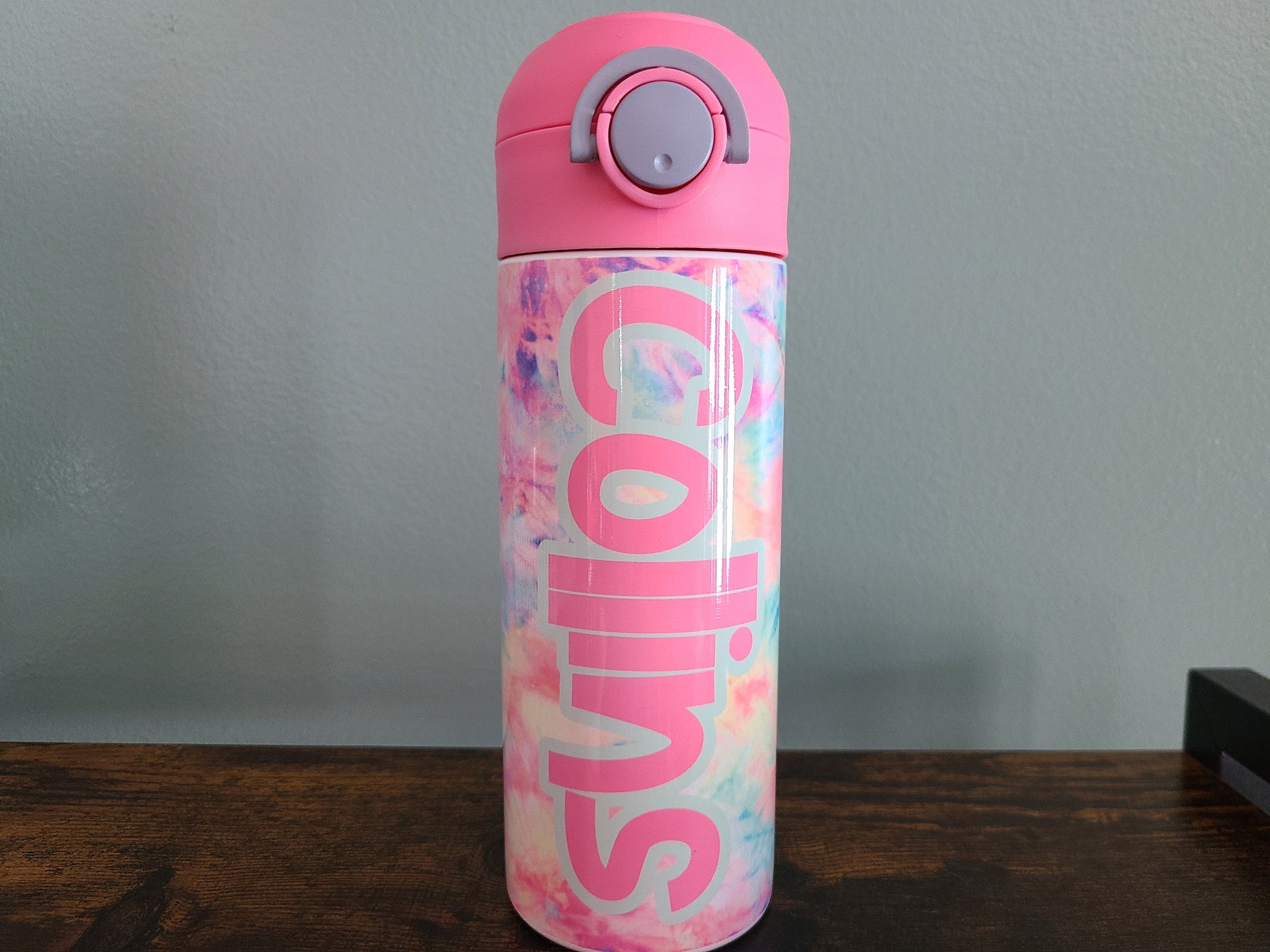 12 oz water bottle with flip top and built in straw. Pink tie dye themed water bottle for kids. Back to school water bottle for kids. Tie dye in pastel colors with a name in pink and pink lid.
